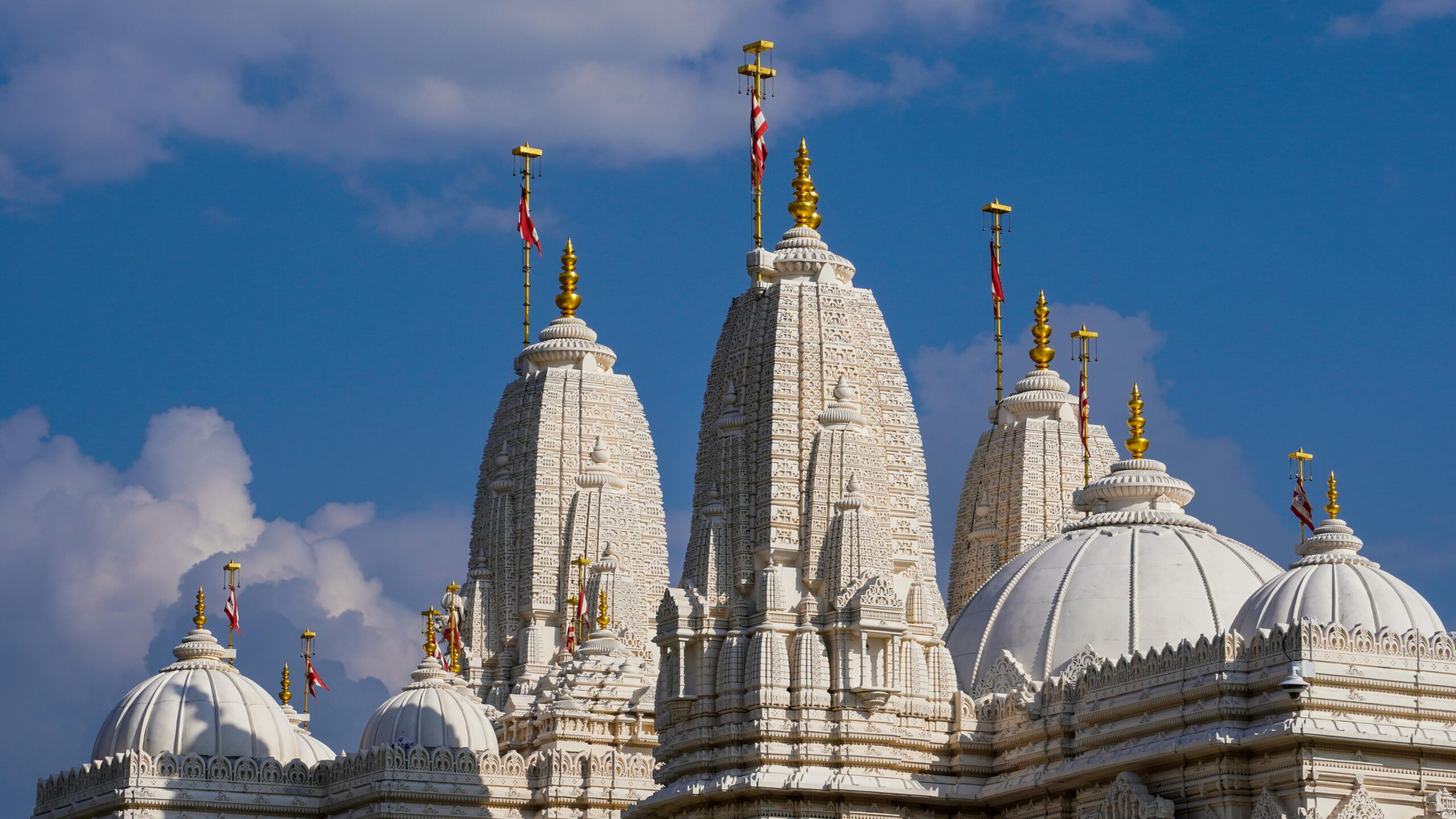 Majestic view of BAPS Shri Swaminarayan Mandir's intricate domes against a blue sky.